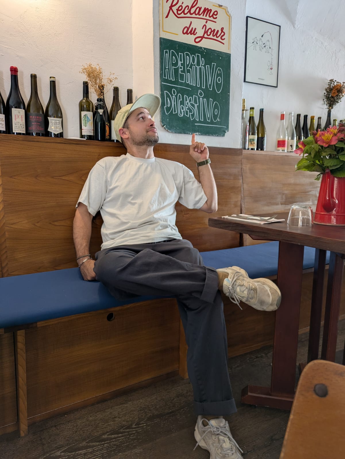 Man sitting in a restaurant booth with wine bottles and a chalkboard menu in the background